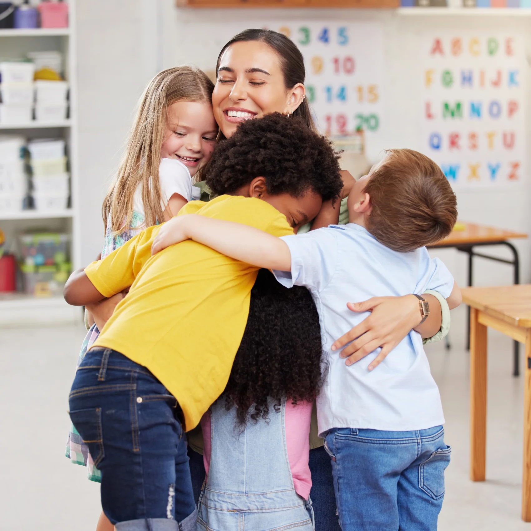Docente abrazando a sus alumnos en el aula, representando el principio de pertenencia en pedagogía sistémica.